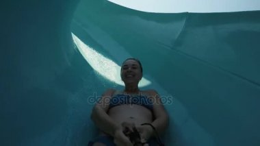 Bir Türk tatil mavi kaydırağı bir aquapark içinde aşağı kayan bir gülümseyen kadın neşeli bir görünümünü.                                          