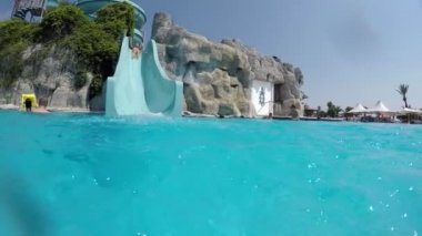 Kemer, Türkiye - Temmuz 18, 2017:A bir Türk aquapark yüksek mavi slayda yaz aylarında Taşınılan bir kadın neşeli görünümü. Mavi suları iyi bak.  