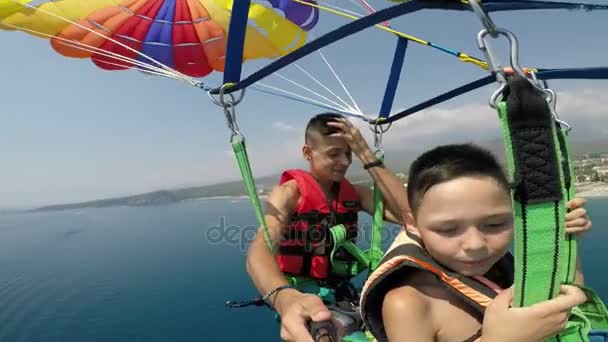 スローモーションで Selfie を作るモーター ボートに引かれたカラフルなパラシュートのトルコのリゾート地の上を飛んで 人の男の子の素晴らしい景色 — ストック動画