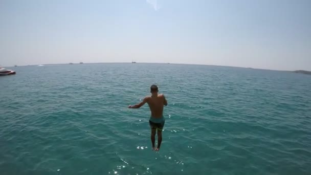 色とりどりのショート パンツがスローモーションで夏にトルコ リゾートで輝く青い海でジャンプで陽気な男の印象的なビュー — ストック動画