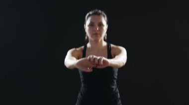 Bir at kuyruğu ile ince kadın mekik mekik siyah singlet ve pantolon giymiş yapan bir fitness eğitmeni siyah stüdyo A harika manzarasını bir yoga mat üzerinde yapar. Siyah bir spor salonunda enerjik yapıyor. 