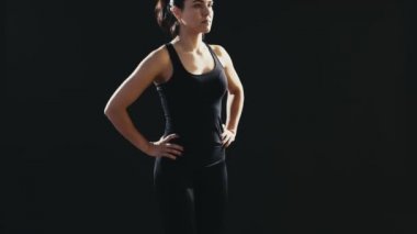 Bir at kuyruğu ile sportif kadın lunges bir mat siyah bir stüdyoda lunges geri bir fitness eğitmen cesaret verici bir görünümünü siyah bir sportif takım elbise giymiş geri. Siyah bir spor salonunda professionaly yapıyor. 