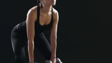 İnce kadın ileri ileri metalik dumbbells ile virajlı ve ileri bir sportif spor salonunda kendini eğitimi sırasında görünüyor ince bir kadın etkileyici bir manzara sportif bir spor salonunda metalik dumbbells ile eğiliyor