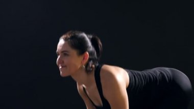 Genç kadın ileri ileri metalik dumbbells ile virajlı ve ileri bir sportif spor salonunda kendini eğitimi sırasında görünüyor ince bir kadının heyecan verici bir görünüm sportif bir spor salonunda metalik dumbbells ile eğiliyor