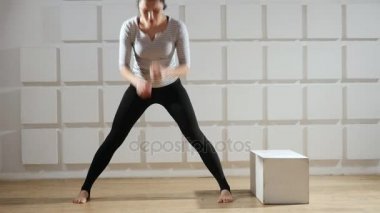 Sportif kadın duruyor ve bacaklarını ileri enerjik viraj standları ve bacaklarını forwardd ve bacaklarını bükme süre geniş tutar atletik bir kadının bir tshirt ve siyah pantolon eğitici bir görünümü geniş tutar.