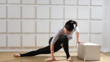 Atletik kadın ileriye doğru bir hamle yapar ve bir küp dokunmadan süre ileriye doğru bir hamle yapar ve sportif bir spor salonunda germek için vücudu bir kenara dönüyor genç bir kadın bir alıcı görünümünü uzatmayayeltenmişti vücudu bir kenara döner.