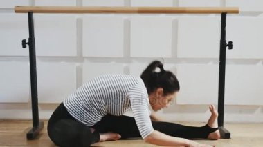 Atletik kadın oturur, bacaklarını uzanır ve bir spor salonunda profesyonel olarak ince bir kadın fitness uygulamaları ve sportif bir spor salonunda oturuyor eğitici bir görünümünü görevini yerine getirmektedir. O bacaklarını uzanır ve bacağı için etkin bir şekilde görevini yerine getirmektedir