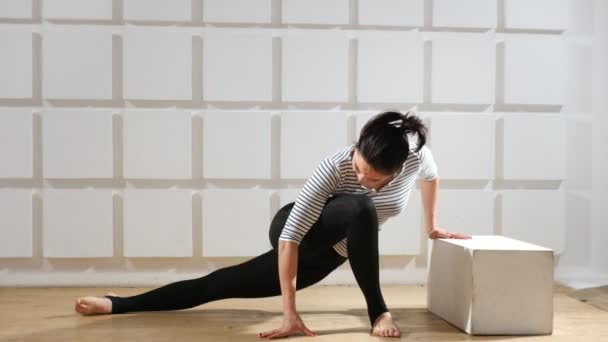 Athletic woman does a forward lunge and turns her body aside to stretch out A catching view of a young woman who does a forward lunge while touching a cube and turns her body aside to stretch out in a sportive gym. — Stock Footage Athletic Woman Does Forward Lunge Turns Her Body Aside Stretch Stock Footage