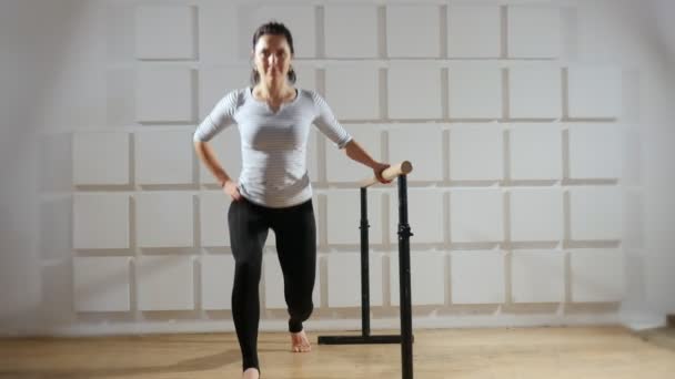 Sportive woman does sit-ups keeping a wooden crossbar actively in a gym An exciting view of a slender woman with a pony tail who does sit-ups keeping a wooden crossbar. She sits down while doing a forward lunge. — Stock Footage Sportive Woman Does Sit Ups Keeping Wooden Crossbar Actively Gym Royalty Free Stock Footage