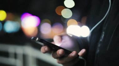 Adamın elleri bir semt kışın cadde üstünde a smartphone perde bilgileri cep telefonunu ekran dokunaklı ve akşamları bir semt bkurred ışıkları ile cadde üzerinde biraz bilgi arayan erkek el sanat konusunda hava atan bir closeup arayın 