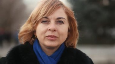 Sarışın kadın siyah kürk paltolu bir şehir sokak durumda ve kış bir güzel sarışın kadın gülümsüyor standları bir şehir sokak ve mutlu olmak gülümsüyor. O bir siyah kürk manto giyer ancak kışın sıcak bir şapka yok.
