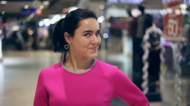 Genç kadın smartens ve tam smartens kadar bir genç esmer kadının bir at kuyruğu ile Sunni Noel A komik manzaraya bir alışveriş merkezi içinde mutlu bir şekilde gülümsüyor ve gülümsüyor Xmas ruh alışveriş Noel giftsy ile.