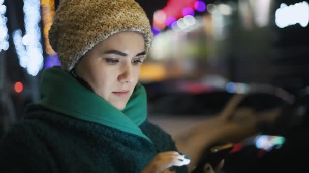 在冬天的晚上 有魅力的女人用她的智能手机在户外工作 Impressiveview 的女人站在城市街道上 在冬天触摸智能手机屏幕 — 图库视频影像