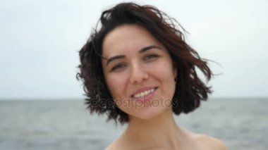 Genç kadın gülümsüyor yaz slo-mo duran dalgalı saçlı genç bir esmer woamn iyimser bir bakış, Karadeniz sahilinde mutlu ve yavaş hareket yaz'Karadeniz kıyısında mutlu bir şekilde gülümsüyor.         