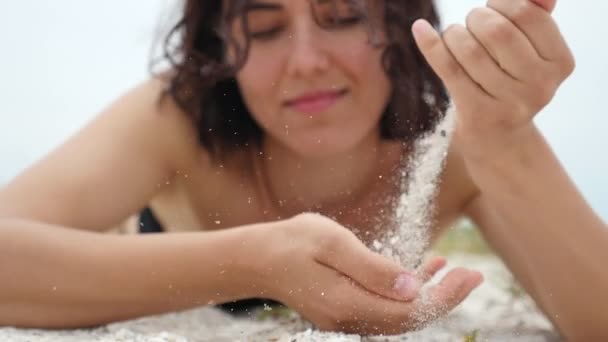 若い女性黒海のビーチに位置し スローモーション黒海の海岸にある 一握りの砂を取り スローモーションで夏にダウンそれをふるい若い女性の素晴らしいクローズ アップ夏の砂をふるい — ストック動画