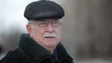 Bir kürk manto bilge gri saçlı adam anlamına gelir ve bir impressiveview üst düzey bir adamın bir deri kürk ceket, kap ve bir şehir sokakta duran ve Xmas hediye hakkında düşünme glassses, kışın bir sokakta .