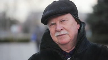 Bilge bir sokakta bir deri kürk ceket gülümsüyor adam kışın duran bir komuta sizde bir deri kürk ve deri kap içinde heyecan verici bir görünümü bir şehir sokak ve Merry Xmas için bekleyen gülümsüyor gri.