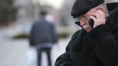 Deri kürk paltolu komuta sizde cep tarafından bir sokakta kışın diyen bir gri saçlı adam bir deri kürk ve deri kap içinde etkileyici bir manzara onun cep telefonuna bir şehir tarafından sokak kışın çağırır.