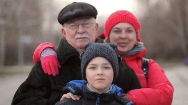 Mutlu gri saçlı dedesi sarışın kızı ve oğlu kışın hugs onun deri şapka ve kahverengi kürklü üst düzey bir erkekte etkileyici bir manzara kat kim yürekten kışın orta yaşlı kızı ve onun çocuk kucaklayan