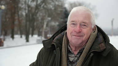 Mutlu gri başlı adam anlamına gelir ve slo-mo kışın gülümsüyor. Eski bir bilge adam iyimser bir closeup bir semt slo-mo kışın cadde üzerinde duran bir koyu yeşil anorak giymiş. Neşeli görünüyor