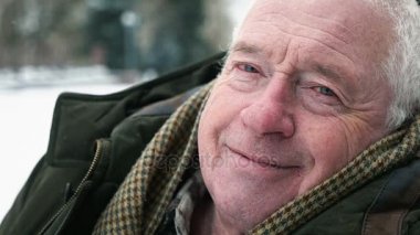 Gri başlı standları ve gülümsüyor yorgun slo-mo kışın ihtiyar. Eski bir bilge adam şaşırtıcı bir closeup bir semt slo-mo kışın cadde üzerinde duran bir koyu yeşil anorak giymiş. Overweary görünüyor.