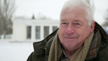 Gri başlı standları ve gülümsüyor biraz slo-mo kışın ihtiyar. Bir heyecan verici eski bir görünümü ve bilge adam bir semt slo-mo kışın arabalar taşınmasıyla cadde üzerinde duran bir koyu yeşil anorak giyinmiş.