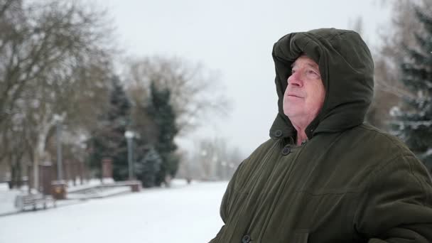 沉思的灰头男人坐在那里 想着他在斯洛伐克的冬天的生活 一个老男人的原始看法 他的头上坐在一条小巷的长凳上 在斯洛伐克的冬天里抬头皮猴 — 图库视频影像