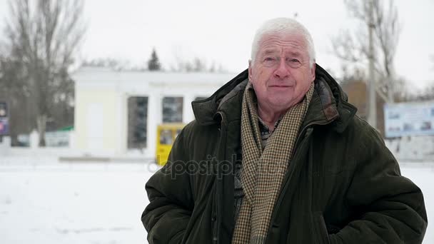 在斯洛伐克的冬天 聪明的灰头人站着微微的微笑 一个古老的智者穿着一个深绿色的皮猴谁站在一个城市的街道上覆盖着大雪在冬季斯洛伐克 莫惊人的看法 — 图库视频影像