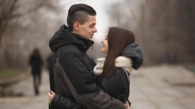 Genç çift stand ve birbirimizi mutlu bir şekilde duran ve birbirlerine şefkatle kışın güzel bir sokak sarılma genç bir çiftin etkileyici bir manzara kışın bir sanatsal sokak üzerinde sarılmak. Gülümse ve kimse fark