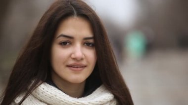 Uzun gevşek saçlı Glamour kızı romantik bir sokakta güzel bir esmer kız kış A closeup ile uzun bağsız kıl görünüyor. O kabarık beyaz kaşkollu bir sokakta ile kışın duruyor
