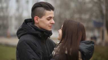 Genç çift gülümse ve komik bir Eskimo gülümseyen ve burunlarını ipuçları basarak genç bir çifti neşeli bir görünümünü bir semt kışın cadde üzerinde öpmek yapmak. Kendi Escimo öpücük bir şehir kış aylarında sokak romantik görünüyor