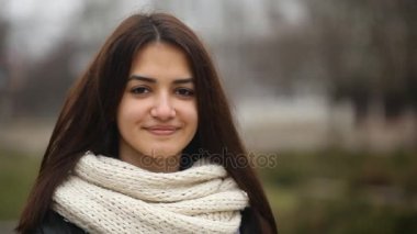 Akıllı kız kış A closeup içtenlikle gülmeyen çekici bir kız uzun saçlı bir sokakta mutlu uzun bağsız kıl gülümsüyor. O kışın beyaz bir eşarp ile zarif bir siyah ceket standları