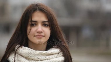 Hoş kız uzun bağsız kıl gülümsüyor içtenlikle mutlu olmak gülmeyen bir çekici kız kış A closeup bir sokakta biraz ile. O kışın beyaz bir eşarp ile şık bir siyah ceket standları