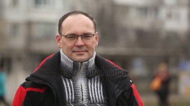 Gözlük ve sportif zipup jaket orta yaşlı bir adamın olumlu bir görünüm iyimser bir semt kışın güneşli bir cadde üzerinde neşeyle bir şehir sokak kışın güneşli bir günde bir orta yaşlı adam gülümsüyor gülümsüyor.