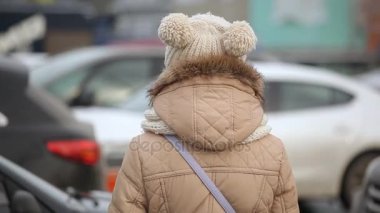 Komik kız bir anorak ve örme şapka yepyeni bir araba görünüyor ve geri beyaz yepyeni bir araba ayakta örme şapka içinde toplar, kürk anorak, neşeli bir genç kadın inanılmaz bir görünümünü açar. O geri döner ve gülümse