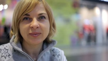 Neşeli sarışın kadın gülümsüyor ve bir alışveriş merkezi kafeterya gülümseyen ve bir alışveriş oturan bob saç modeli sarışın bir kadınla Kış A neşeli görünümünde oturur kafeterya alışveriş merkezi. Bir gri zipup kazak kız