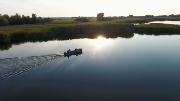 在夏季灿烂的夕阳下漂浮在 Dnipro 河上的一艘摩托艇的空中拍摄 一个艺术鸟的眼睛看着一艘汽艇 人们在风景如画的 Dnipro 河上移动 在日落时用芦苇和手杖覆盖着绿色河岸 — 图库视频影像