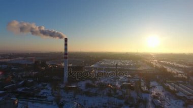 Bir yükseltilmiş sıcak gaz baca kışın muhteşem bir günbatımı, karanlık bir duman akış ile Kış A kuş bakışı devasa baca, günbatımında karanlık dumanlı hava vurdu. Cityscape endüstriyel ve parlak
