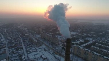 Beyaz duman ve kışın cityscape ile yüksek bir Endüstriyel boru hava atış kışın gün batımında yoğun duman bir akışı ile tüp özgün bir kuşbakışı görünümü büyük bir tuğla. Ukrayna'da bir endüstriyel alanda standları. 