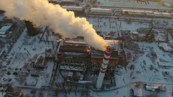Aerial up down shot of a high hot gas tower with white smoke at sunset in winter An up down view of a high tower with a slow flux of smoke at a wonderful sunset in winter. It stands near a plant. and houses. — Stock Footage Aerial Shot High Hot Gas Tower White Smoke Sunset Winter Video Clip