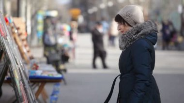 Şık bir orta yaşlı kadın resimleri sanat sokakta sonbaharda bir artisticview bir pitoresk park sokakta sonbaharda sergilenen resimler bakar bir esmer kadının örgü şapka ve kürk görünüyor 