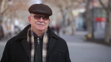 Güneş gözlüğü standları ve düz bir kapak şık bir gri saçlı adam sonbahar Anoptimistic görünümünü park sokakta gülümsüyor neşeli bir komuta sizde kareli atkı ve güneşli bir günde bir park sokak üzerinde duran güneş gözlüğü 