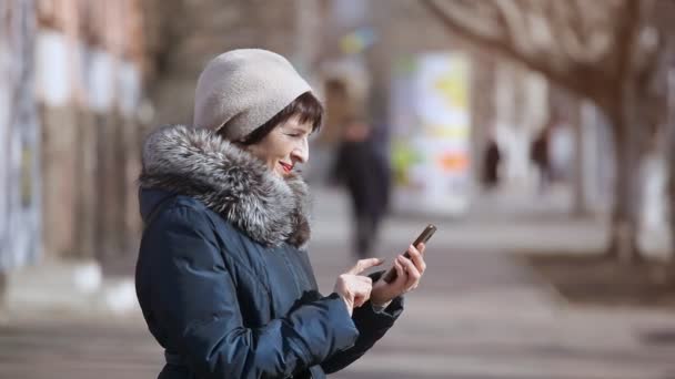 Μια Μελαχρινή Γυναίκα Ένα Πλεκτό Καπέλο Καλεί Smartphone Ένα Σοκάκι — Αρχείο Βίντεο