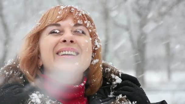陽気な金髪の女性は雪の下に立つし 冬の公園で重い雪の下で毛皮のコートに立っている金髪の女性観が興奮してスローモーションで検索します 彼女はスローモーションで幸せそうに笑ってを見上げる — ストック動画
