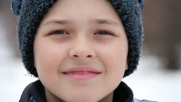 Een Gelukkige Jongen Een Zwarte Gebreide Muts Glimlacht Een Besneeuwde — Stockvideo