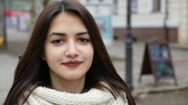 Şık bir kız bir şehir sokak ve gülümseyerek mutlu bir şekilde kışın slo-mo bir şehirde sokak duran uzun bağsız kıl güzel bir kızla etkileyici bir manzara ve gülümser iyimser yavaş kışın standları