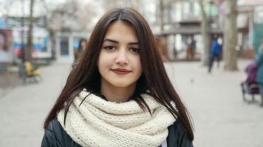Kışın sokak bir şehirde Splendi kız duruyor. O biraz uzun bağsız kıl bir üst sınıf kızla çekimde gülümsüyor ve derin standları ve şık parka ve kışın sokak bir şehirde beyaz kaşkollu gülümsüyor gözleri. 