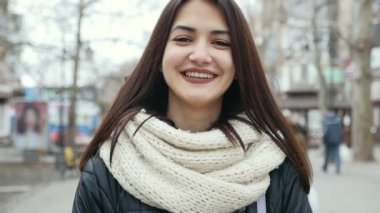 Güzel kız kış aylarında sokak bir şehirde elini kolunu sallaya dönüyor. O mutlu neşeli bir kız zarif bir parka kadar gevşek saç ile çekimde gülümsüyor ve beyaz kaşkollu kışın sokak bir şehirde parklarla. O mutlu bir şekilde gülümsüyor.