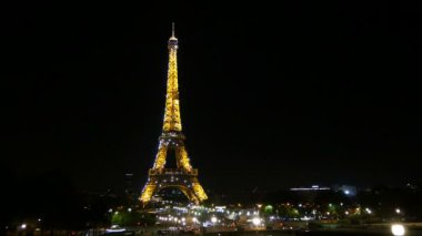 Paris, Fransa - 3 Kasım 2017: Paris'te Eyfel Kulesi bir etkili zaman atlamalı görünümünü. Arabalar onun sütundan altında acele. Geceleri arka aydınlatma parlak sarı vardır