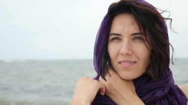 Menekşe mendil başında neşeli bir kızla bir seabeach üzerinde gülümseyen bir rüya esmer kız closeup slo-mo bir sahil üzerinde duruyor. Onun kafasında slo-mo yaz aylarında Menekşe mendil var. Deniz manzarası muhteşem